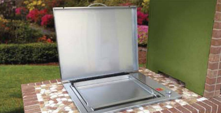 Built-in stainless steel plancha griddle set into a tiled outdoor counter with its lid raised