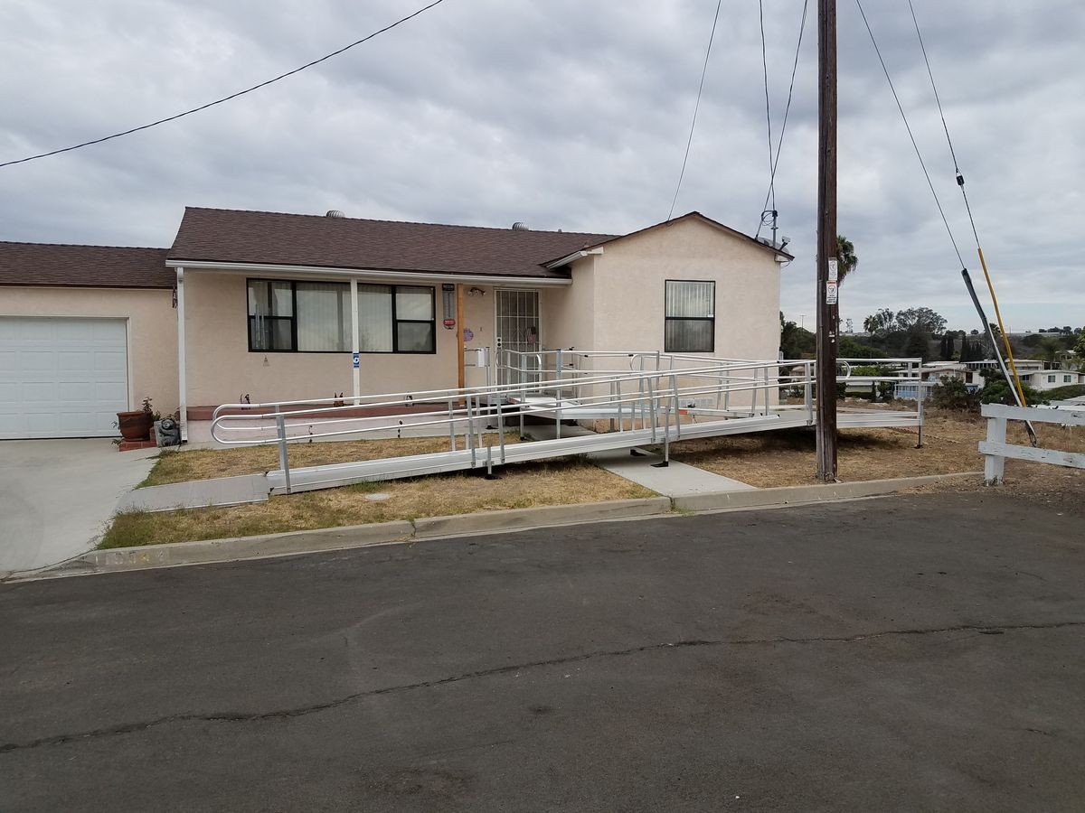 Metal wheelchair accessibility ramp installed in front of a house