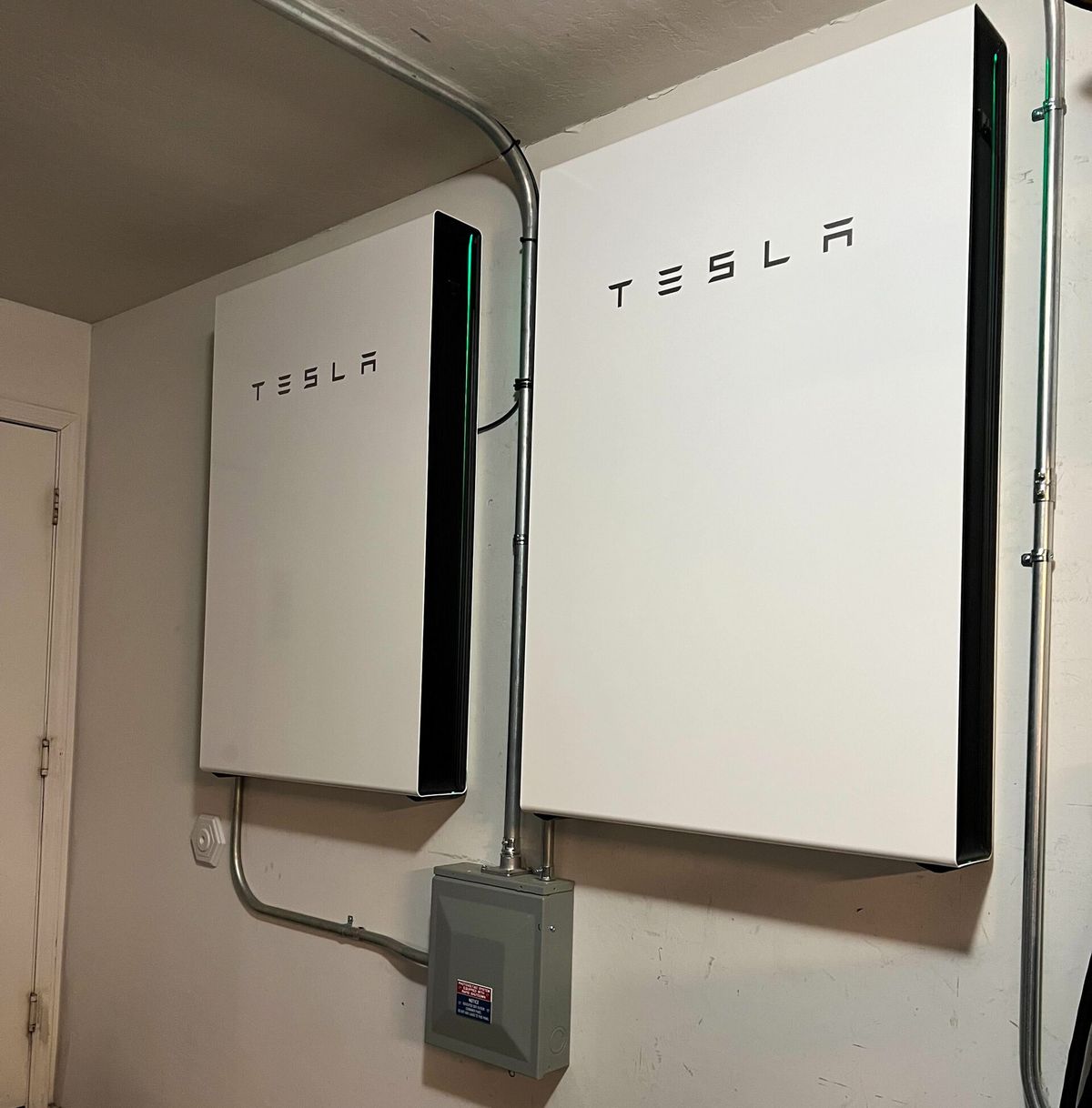 Two Tesla Powerwall 3 home battery units mounted on a garage wall