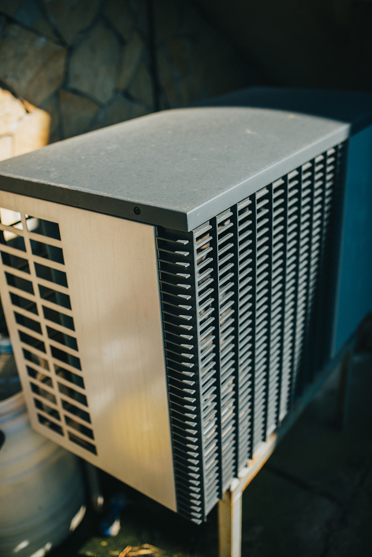 Outdoor air-conditioning condenser unit with louvered vents in a garden