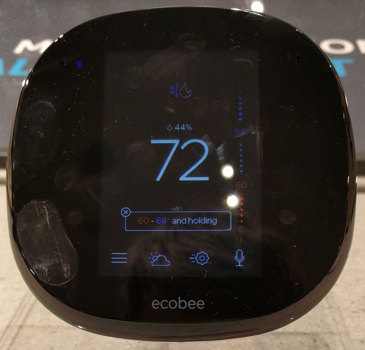 A smart thermostat mounted on a wall showing its home screen