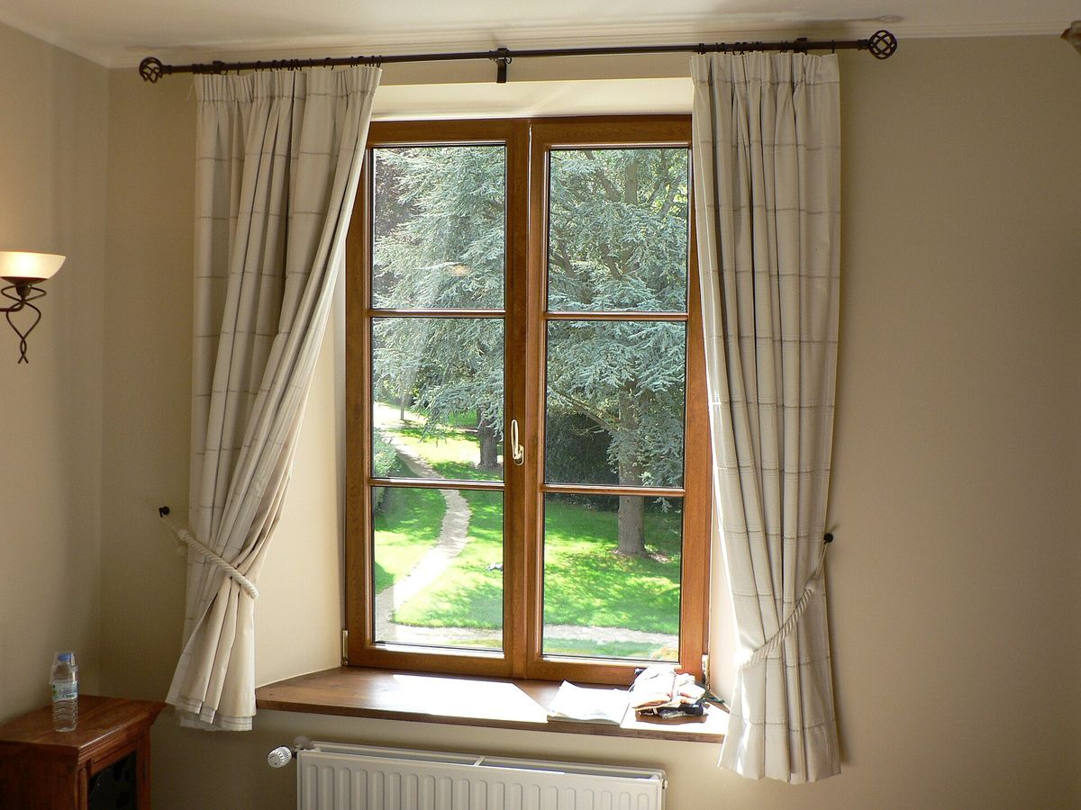 Floor-length curtains hanging on a rod above a tall window