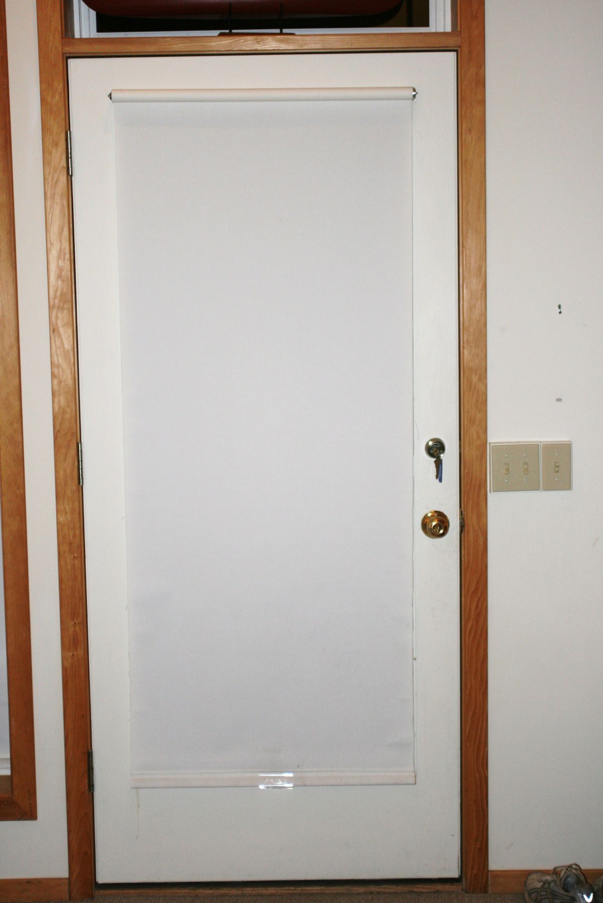 White roller shade covering a door window