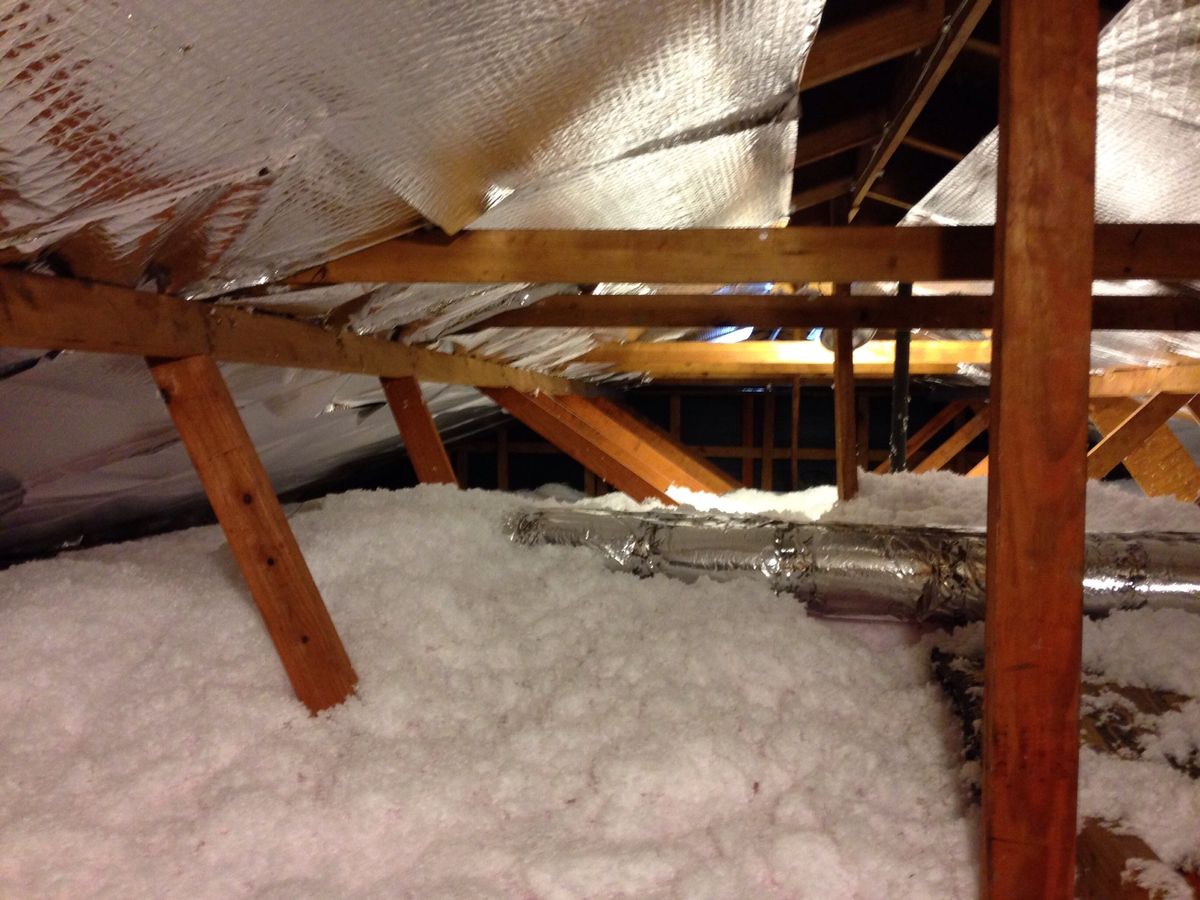 Home attic with blown insulation and flexible HVAC ductwork