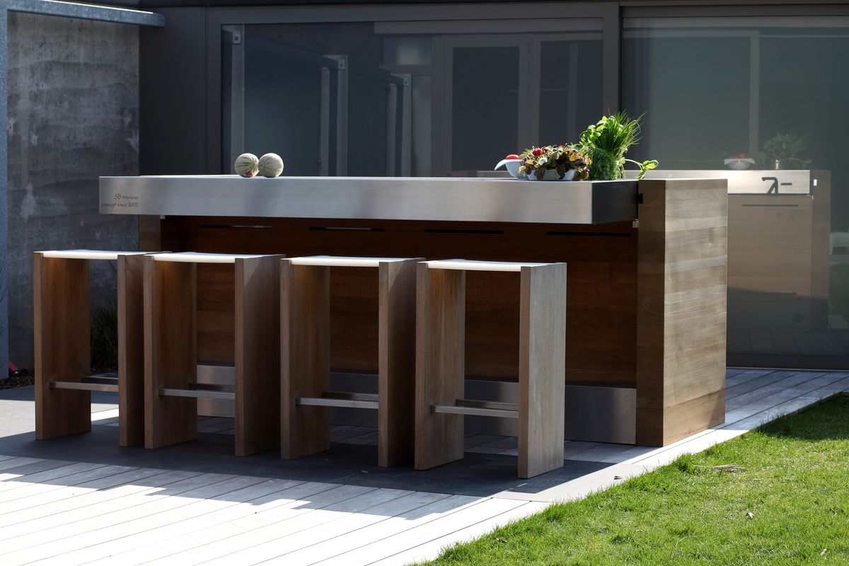 A built-in outdoor kitchen with grill station in a residential garden