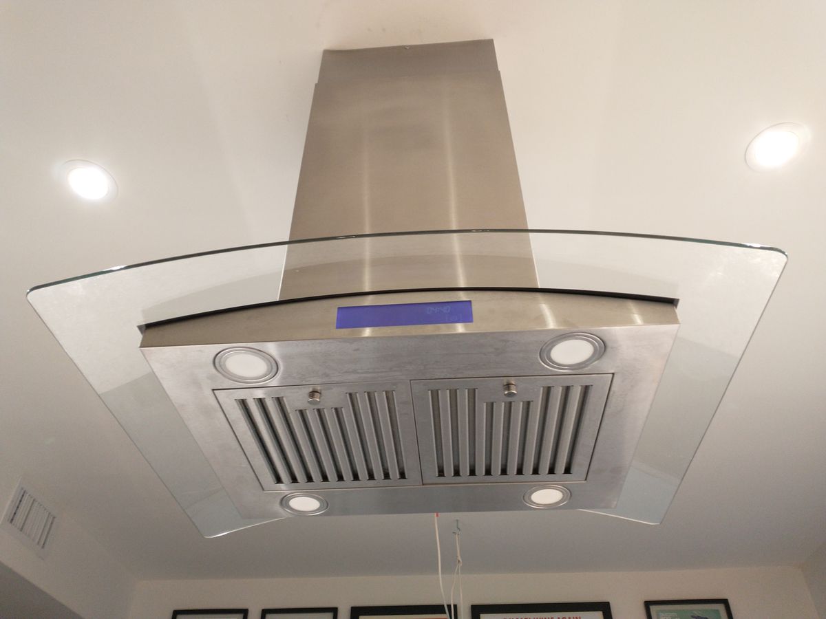 Stainless steel range hood with glass canopy above a kitchen cooktop