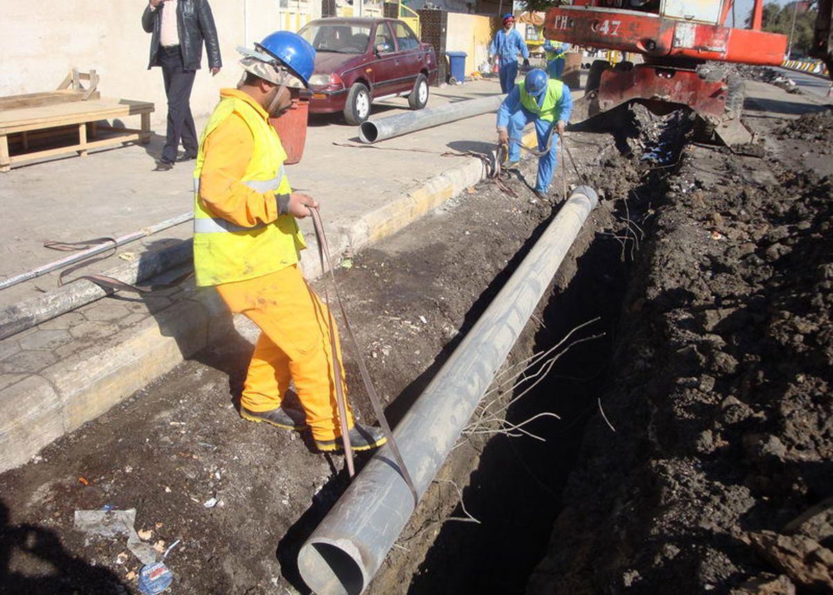 Construction workers laying a large sewer pipe into an open trench
