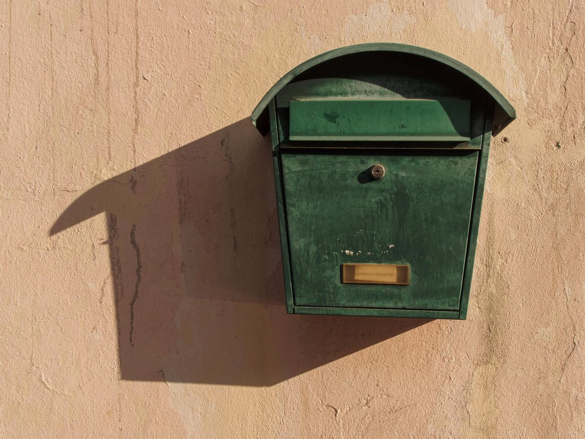 Green wall-mounted mailbox on a home exterior wall