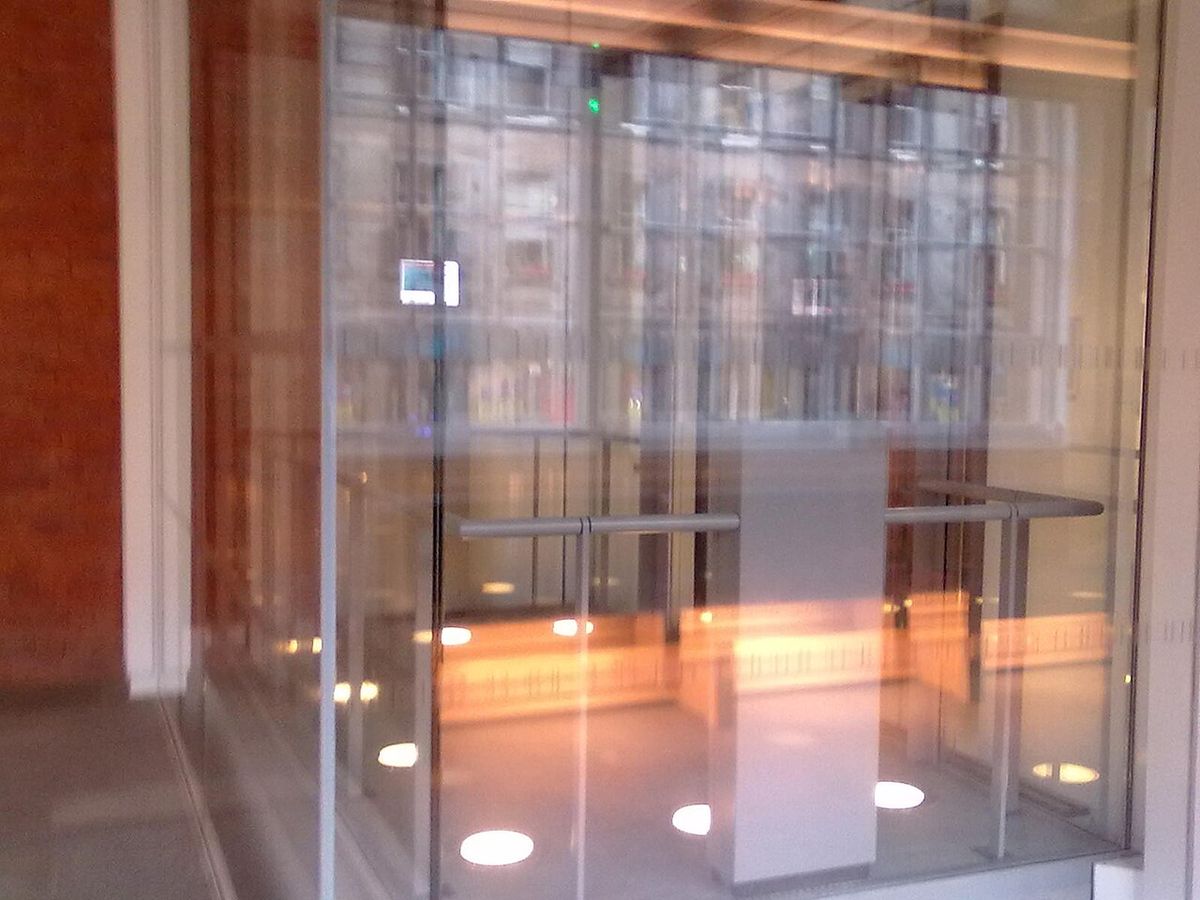Glass-walled elevator cab with transparent panels in a modern building interior
